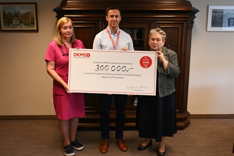 trzy osoby trzymające zdjęcie. Od lewej: dr Katarzyna Żybul kierująca hematologią w SPWSZ; dyrektor Małgorzata Usielska i p. Leszek Lewandowski z Fundacji DKMS
